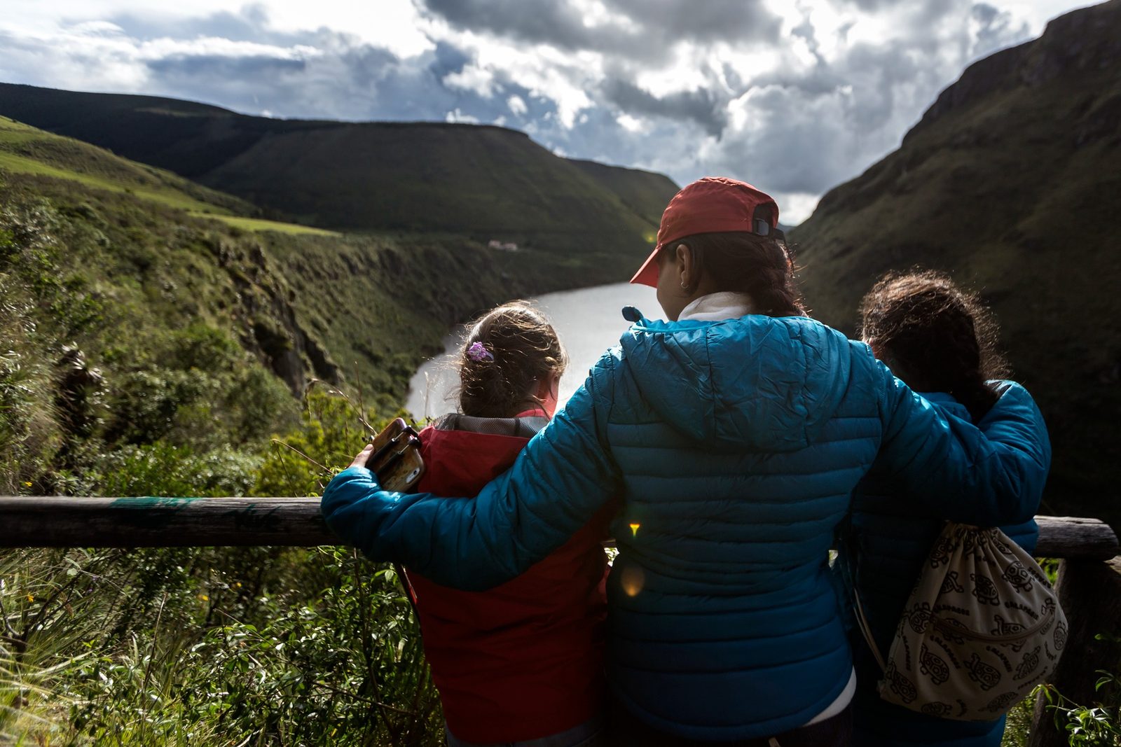 Family viewing an Andean lagoon surrounded by green mountain slopes in the Antisana region