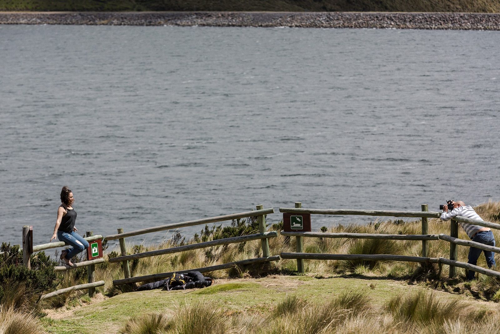 Travelers photographing an Andean lake from a wooden nature lookout in the Antisana area