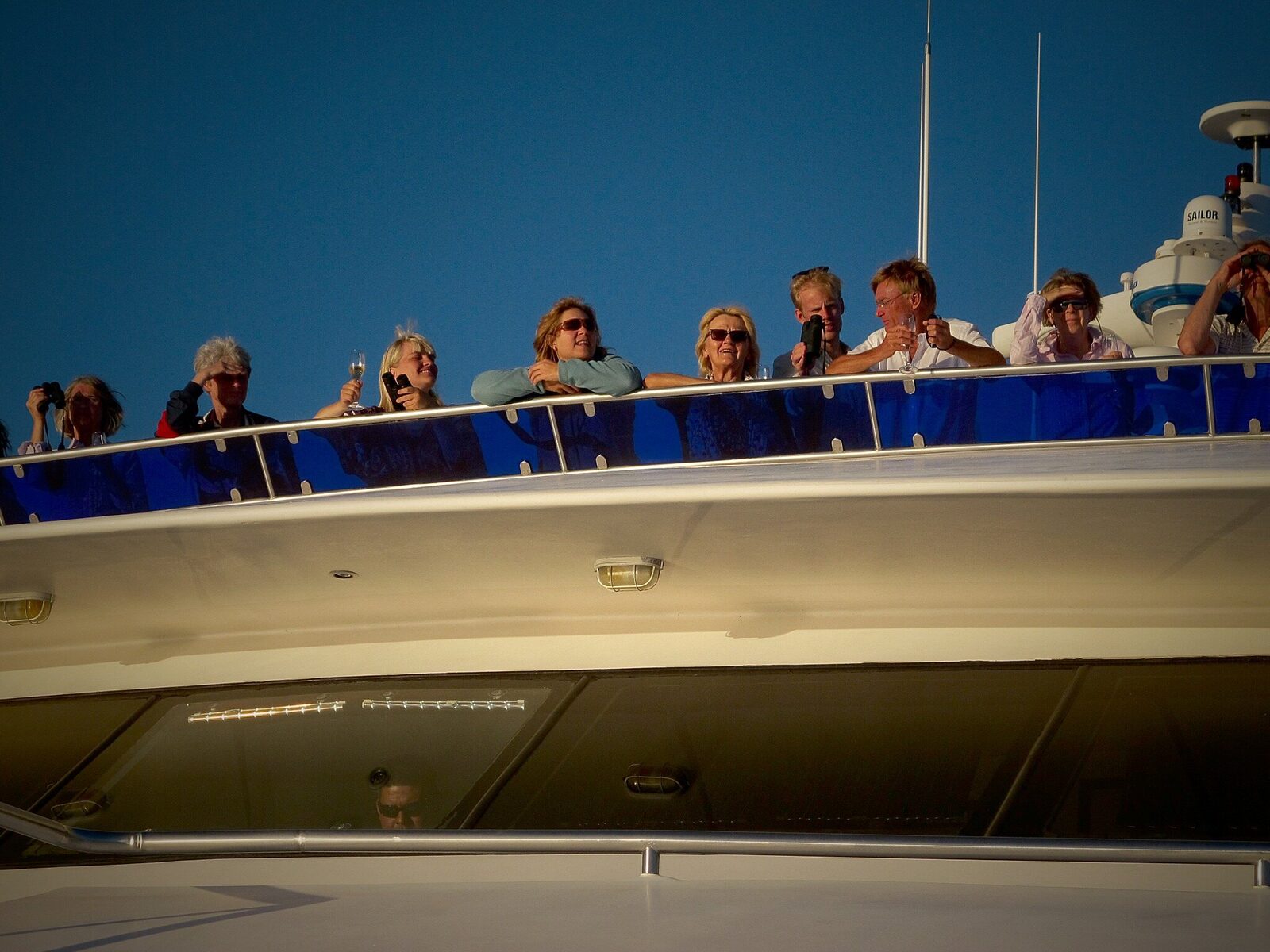 Pasajeros disfrutando de la cubierta superior de un crucero bajo un cielo azul intenso