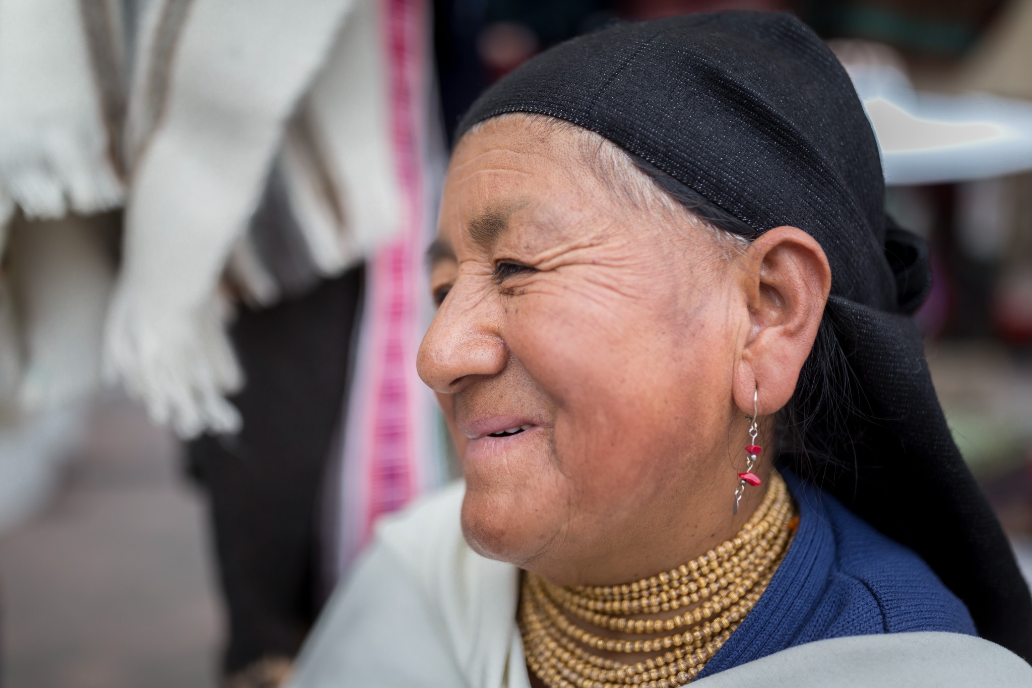 Portrait of an Otavalo indigenous woman wearing a black head covering and layered traditional necklaces