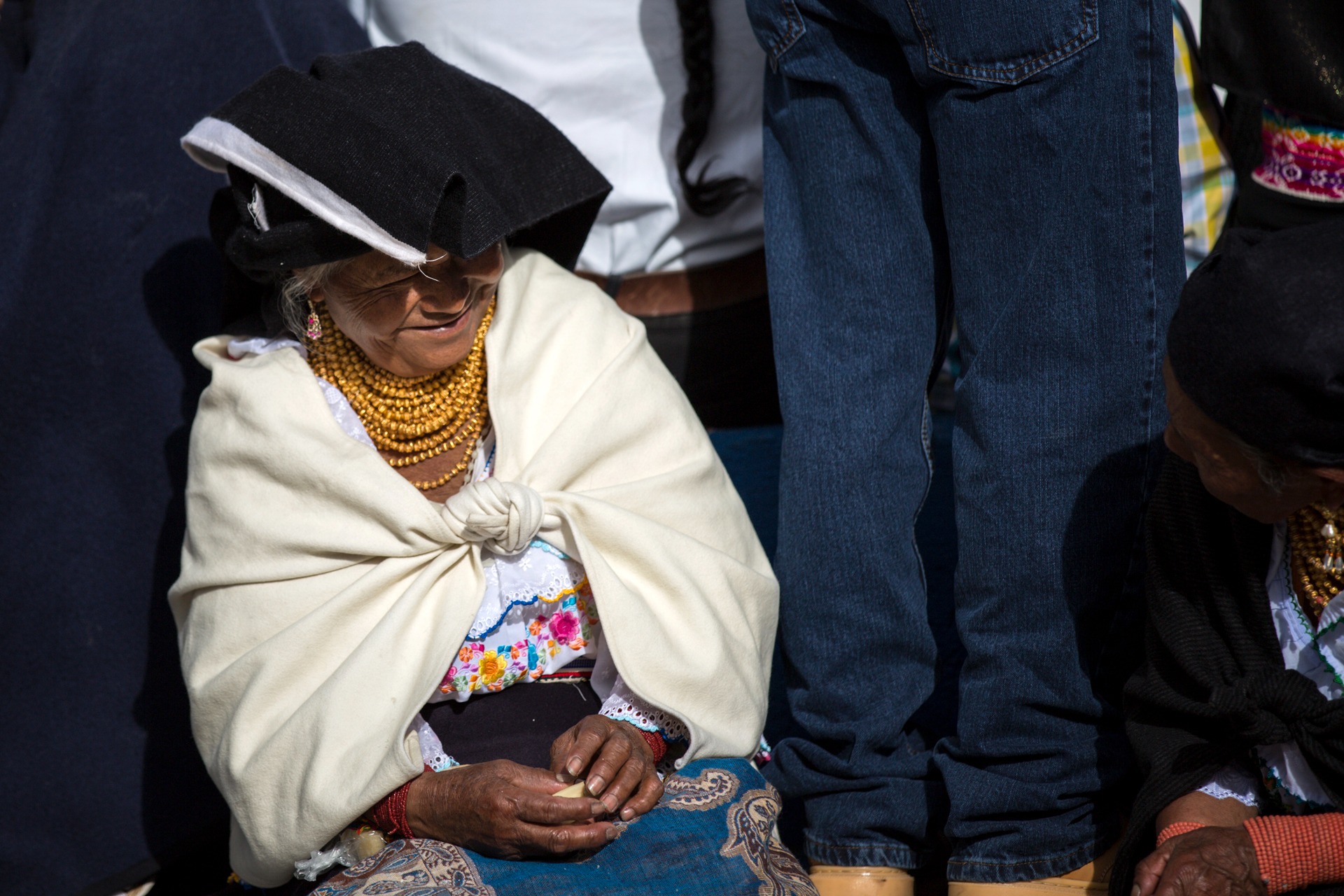 Otavalo indigenous woman wearing traditional white shawl, embroidered blouse and layered gold-colored necklaces