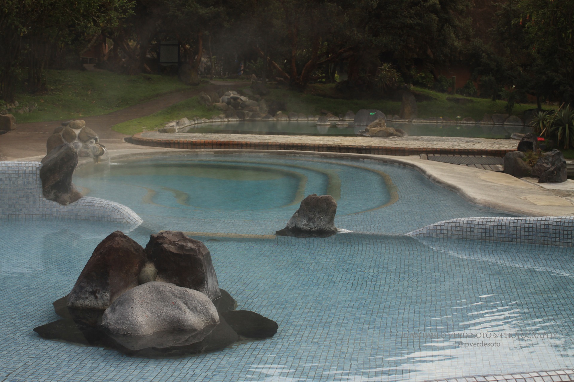 Quiet blue thermal pools surrounded by rocks, trees and mist at Papallacta Hot Springs