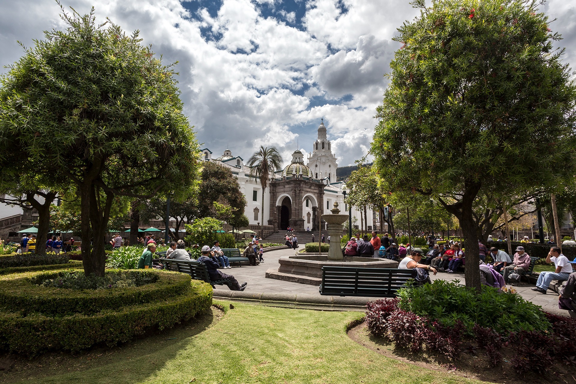 Historic Quito square with gardens local residents and colonial architecture under an Andean sky
