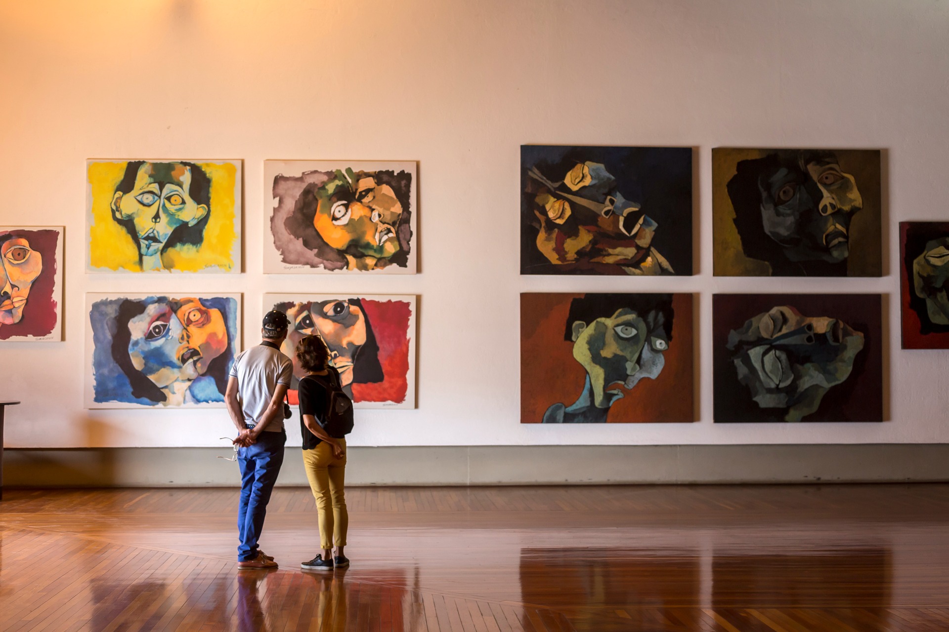 Visitantes que contemplan pinturas modernas y expresivas relacionadas con la experiencia artística de Guayasamín en Quito