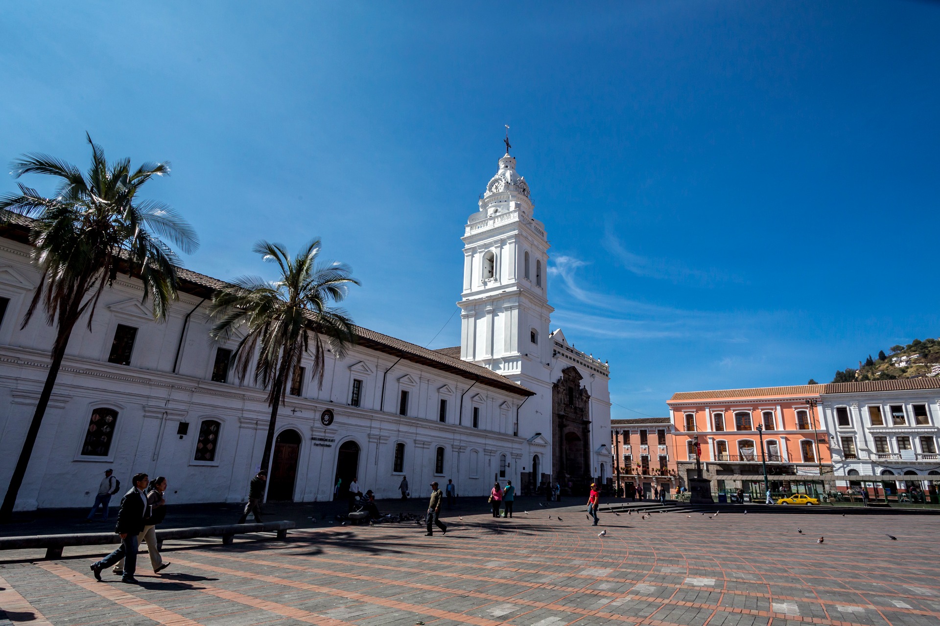 Plaza del centro histórico de Quito, rodeada de edificios coloniales blancos y palmeras