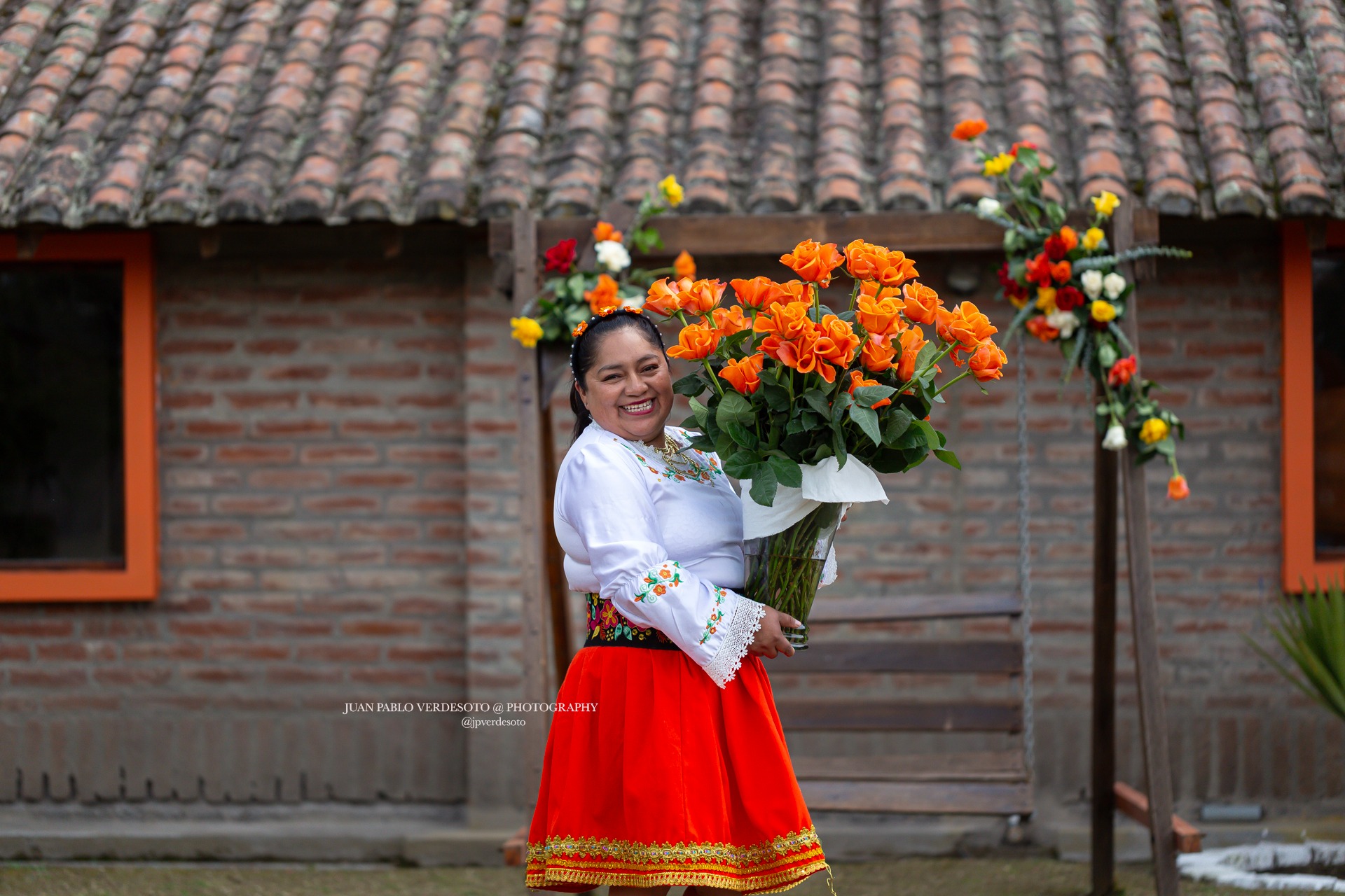 Woman in traditional clothing holding a large bouquet of orange roses in Ecuador