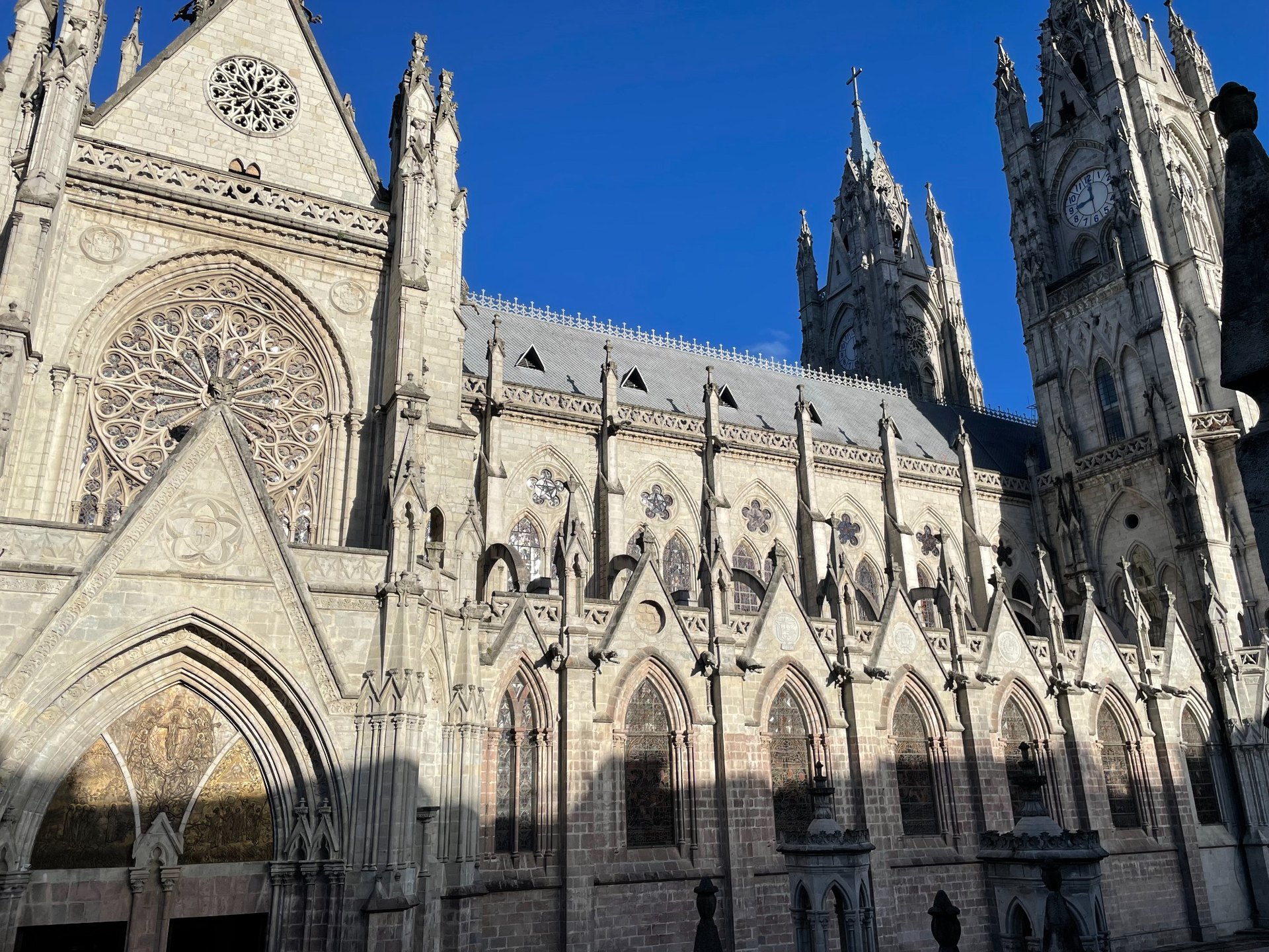 Gothic stone facade and towers of the Basilica in Quito under a deep blue sky