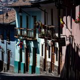 Colorful colonial street in Quito with balconies, tiled roofs and Ecuadorian flags