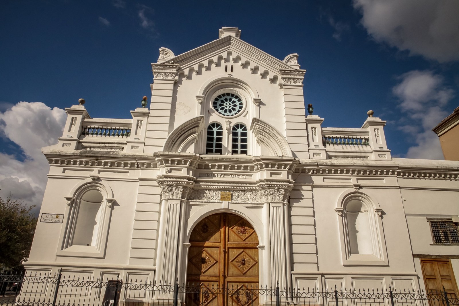 White historic church facade in Cuenca Ecuador under a dramatic blue sky
