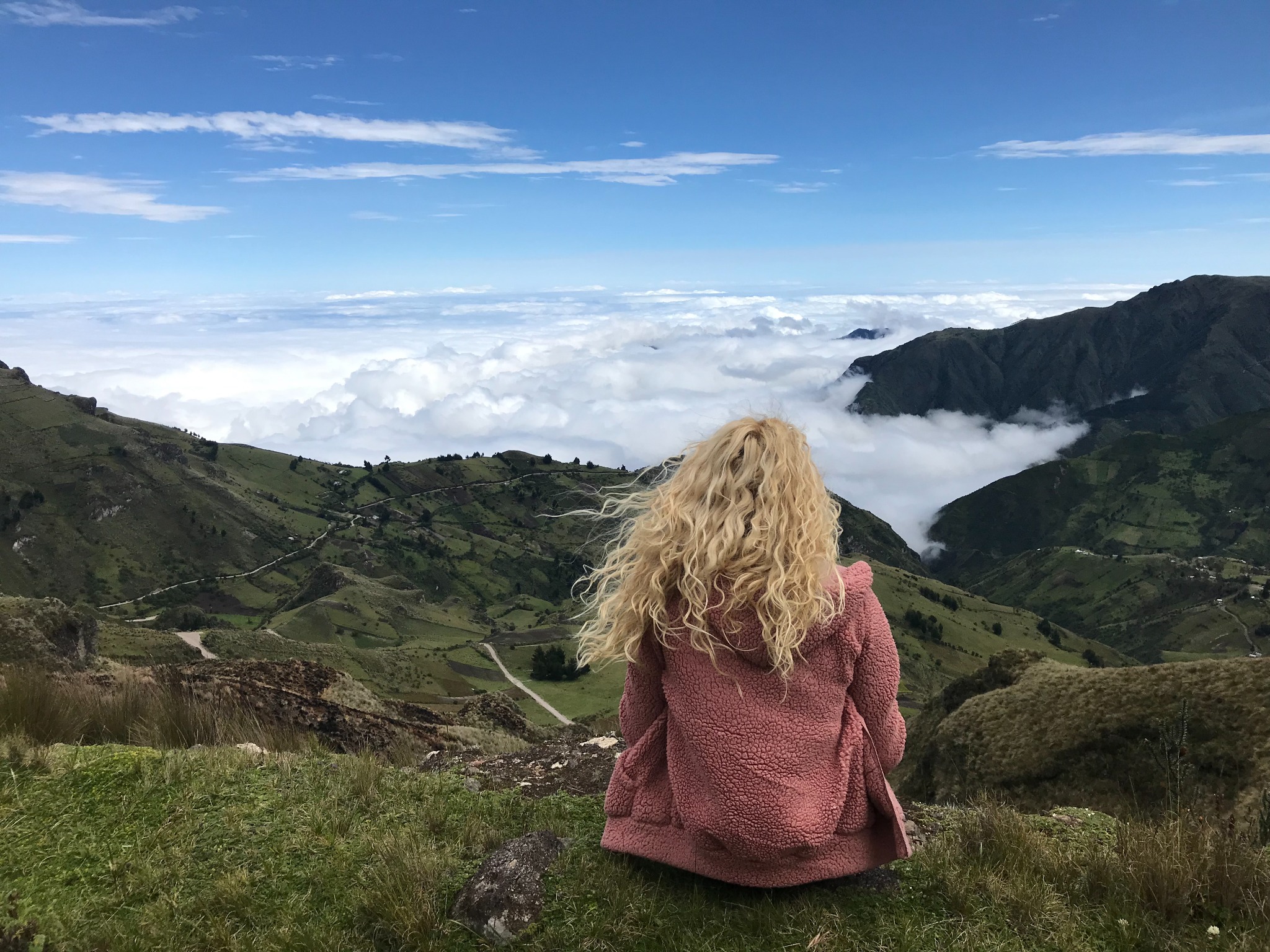 Traveler overlooking high Andean valleys and a sea of clouds along the Quilotoa route in Ecuador