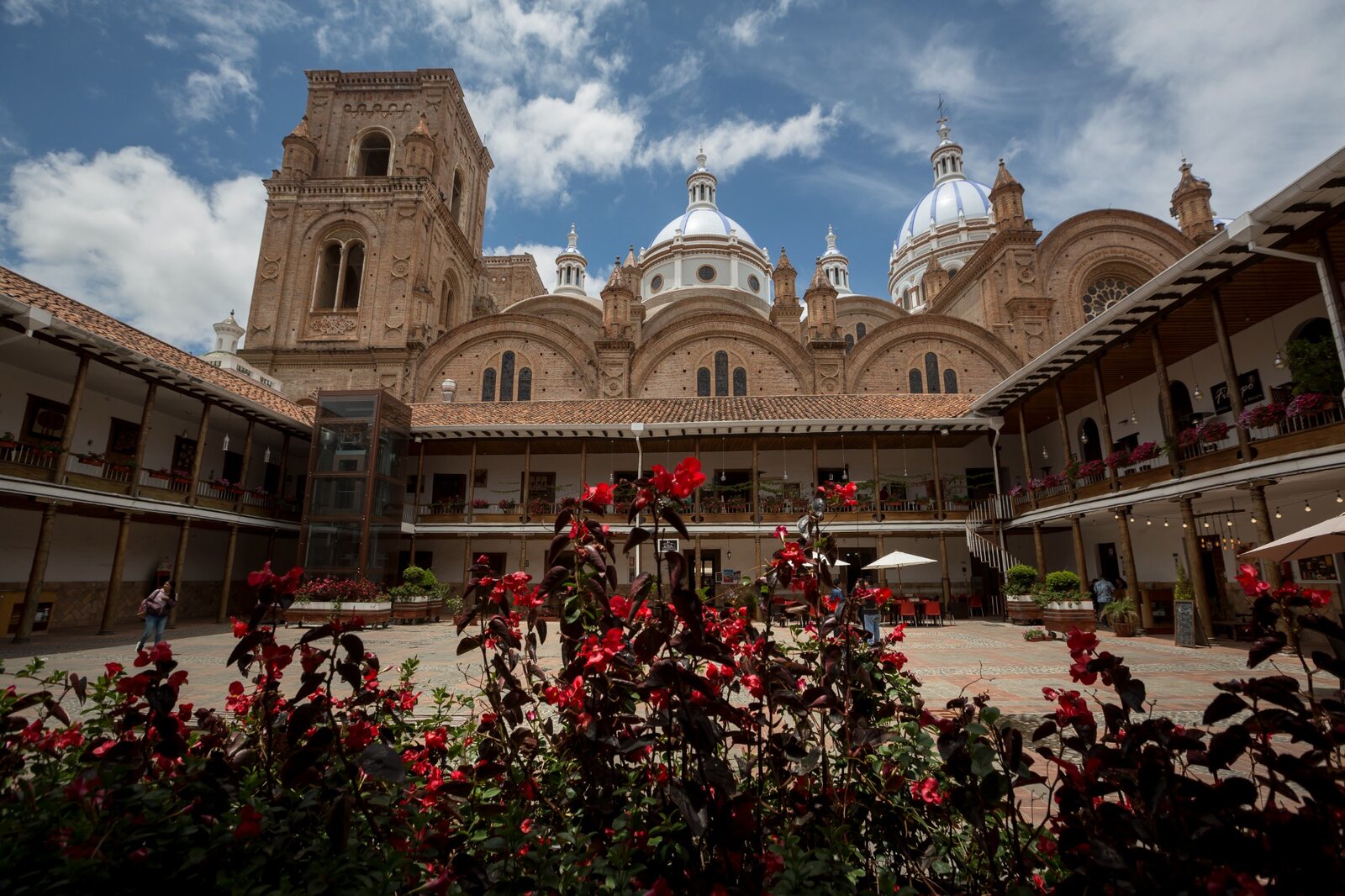 Historic brick cathedral architecture and flower-filled courtyard in Cuenca Ecuador